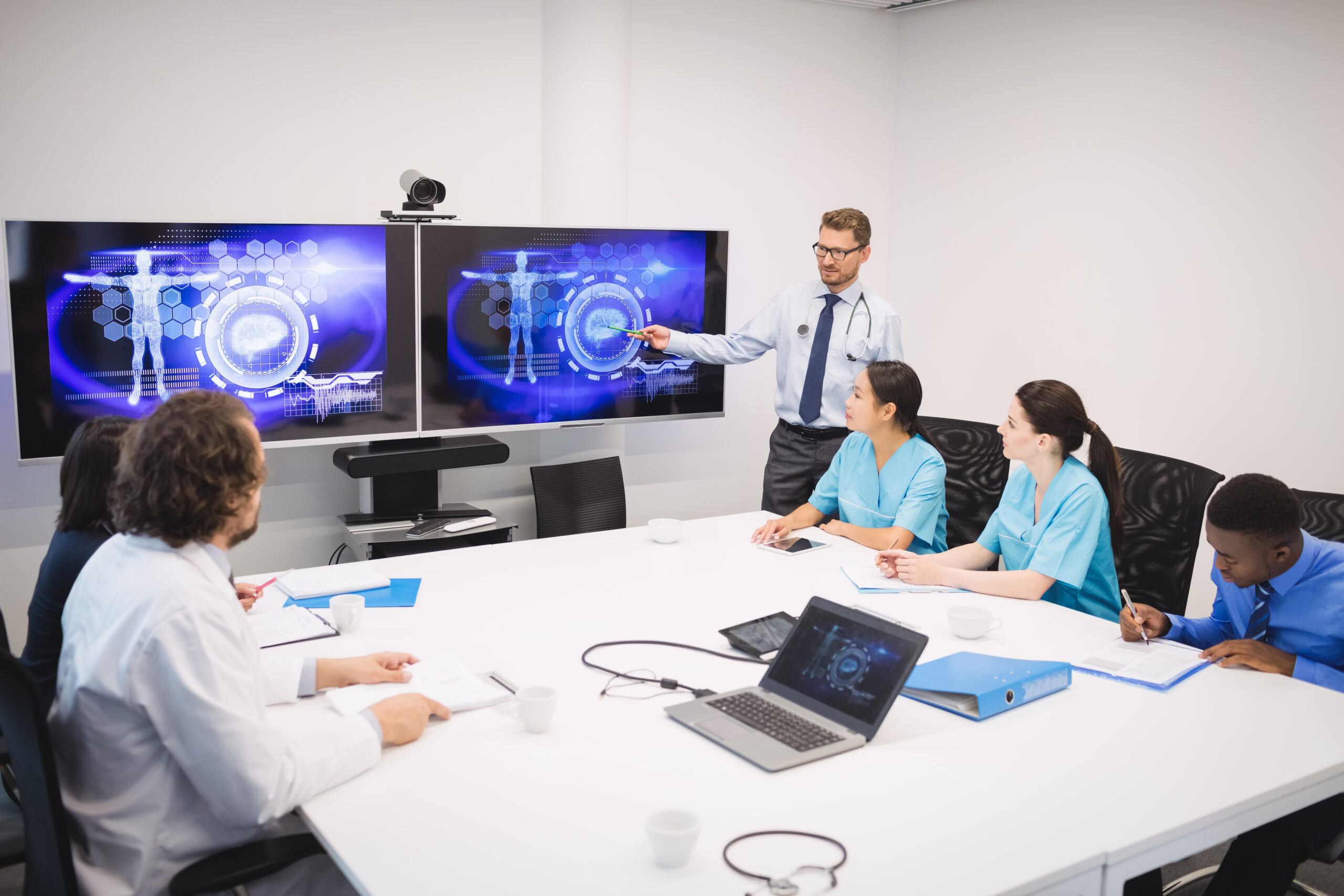 Doctor giving presentation to team of interim doctors at conference room
